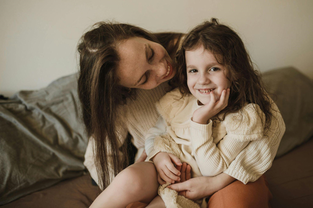 Smiling mother holding her young daughter at home, representing a nurturing child-centered approach to custody arrangements.